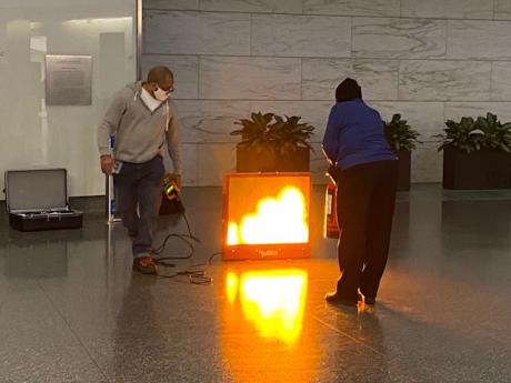 Two OPS Employees standing with a simulated fire for fire extinguisher training