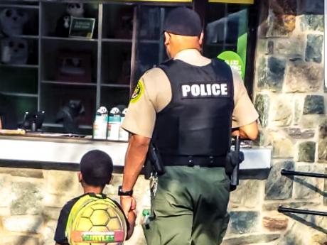 A Zoo Police Officer walks with a small child as they hold hands. 